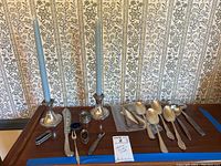 Full lot on table: two candlestick holders with taper candles at left, three napkin rings, salt cellar, sterling utensils and additional flatware at right.
