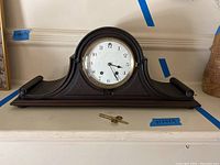 Front view of Seth Thomas tambour mantle clock with key placed in front on white surface.