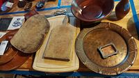 Image showing multiple wooden cutting boards, wooden plates, a wooden bowl, metal trays, and a small wooden vase arranged on a surface.