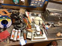 Photo of the workbench with assorted hand tools including screwdrivers, hand saw, grease tubes, and other small tools and hardware.