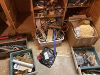 Wide view showing different containers: basket with cords and tapes, box with towels, toolbox, plastic bins with miscellaneous hardware