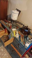 Overview of vintage kitchen items including ceramic canister, kitchen scale, hand grinder, wooden utensils, cookie cutters on a blue chest of drawers.