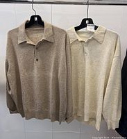 Two sweaters hanging side by side on hangers against white background; shows overall design, color contrast of taupe and cream