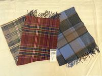 Pair of plaid cashmere scarves laid flat, showing each scarf's distinct plaid pattern and fringe.
