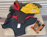 Four custom dog jackets and four collars arranged on a table