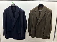 Both blazers hung side by side showing navy and brown colors, single-breasted style and flap pockets