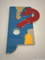 Front view of resin-covered cover showing abstract blue, yellow, and red shapes with circular cutout.