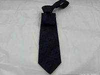 Full view of the black and blue GUCCI silk tie laid flat on a white background, showing the full length and pointed end.