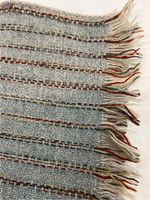Close-up of woven pattern and multicolored stripe accents with fringed edge