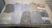 Ten packaged dress shirts arranged in two rows of five on a table