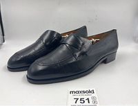Pair of black leather loafers shown angled from the side, showing overall condition and shape.