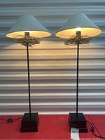 Both lamps illuminated on red surface against corrugated white backdrop