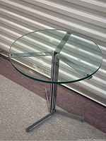 Three-quarter view of glass top side table showing chrome base and feet