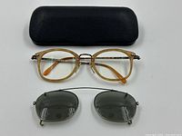 Top-down view of eyeglass frames, clip-on lenses and hard shell case