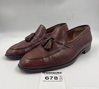 Side/front angle of brown leather loafers showing overall shape, tassels, and sole edge
