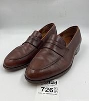 Front three-quarter view of pair showing pebble-grain leather uppers and penny strap detail