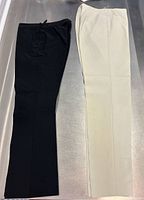 Black and cream Prada pants laid flat side by side on metal surface