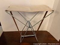 Front view of unfolded seat showing canvas panel and metal X-frame