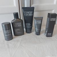 The complete lot displayed on a white surface showing four products unboxed plus a boxed item on the right: antiperspirant deodorant stick, oil control exfoliating tonic, charcoal face wash, face bronzer tube, and boxed dark spot corrector.