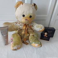 Photo showing the full Ferragamo pattern fabric teddy bear sitting with the Ferragamo Bright Leather shampoo and shower gel tube and the Signorina Misteriosa perfume bottle with box on the side.