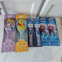 Full lot showing 2 Disney Wet Brush hairbrushes and 2 Oral B Frozen toothbrushes plus replacement heads, all in original packaging.