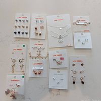 Full view of Joe Fresh branded cards showing various earrings and 3 necklaces laid out on a white surface.