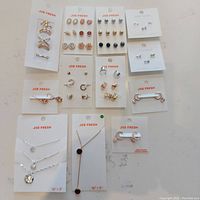 Top view of jewelry cards showing earrings, rings and necklaces all labeled Joe Fresh on white cards.