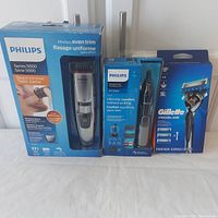 Front view of all three boxed grooming products including Philips Series 5000 beard trimmer, Philips NT3000 nose trimmer, and Gillette Proglide razor with cartridges.