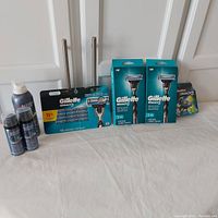 Wide view showing the full lot arranged on a white surface, including Gillette Mach 3 razor handles in packaging, cartridge packs, and Biotherm shaving products.