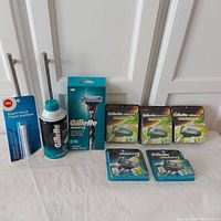 Overview of all items in the lot including razor handle, multiple sealed cartridge packs, styptic pencil, and shaving foam can.