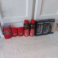 Full lot of Old Spice Swagger deodorant, antiperspirant sticks, body sprays, and Tweezerman grooming kits displayed on white cloth surface against white doors.