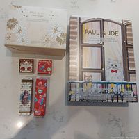 Photo of the entire lot showing the box for the luxurious bath and body collection labeled with Paul & Joe brand, the 2018 makeup advent calendar with illustrated cats, two lip treatment balm boxes, and two hand cream boxes.