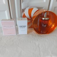 Front view of three perfume bottles and boxes: Givenchy Irresistible and L'Interdit boxed and sealed, Michel Germain Sugarful & Spice bottle in front of its box.