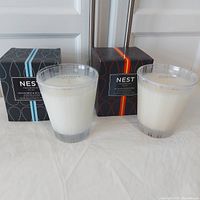 Two Nest Fragrances scented candles along with their boxes, one Ocean Mist & Sea Salt and one Sicilian Tangerine.
