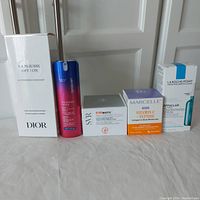 Five skincare products lined up: Dior cleanser, Strivectin retinol serum, SVR radiance cream, Marcelle collagen moisturizer, La Roche-Posay serum. All in original packaging, some boxes open but bottles sealed.