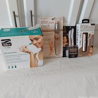 Photo showing the full lot of women's personal care items arranged against white background featuring Silk'n ReVit Microderm and Finishing Touch Flawless products in sealed packaging.