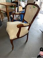 Front and left side view showing the wooden frame, upholstered seat, backrest, and armrests with light fabric wear.