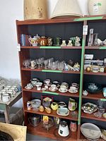 Front view of the wooden bookcase filled with various kitchenware and decorative items, showing shelf arrangement and overall structure.