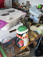 Photo showing Salton portable cooktop box, penguin cookie jar, hand painted wooden shoes, and various kitchen items on table