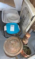 Photo showing stacked white plates, glass baking dish with blue lid, glass cake pan, serving tray, and visible copper items to illustrate full lot contents and condition.