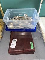 Plastic bin filled with assorted Gorham Co silver flatware pieces sitting on top of a wooden canteen case.