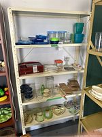 Front view of metal shelving unit showing all shelves with various household items on shelves (not included in sale).