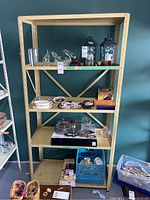 Front view of metal shelving unit with four shelves, holding various household items not included in sale.