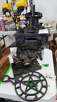 Photo showing miniature cast iron stove with two small pots on top, metal car in front, and iron trivet below.