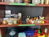 Full view of shelf with assorted candles, salt and pepper shakers, and kitchenware items.