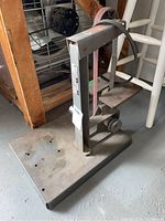 Heavy metal frame sander/grinder base and vertical support with belt system visible.