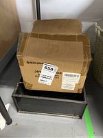 Closed cardboard box sitting inside dark metal shelf or container