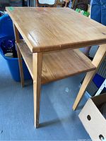 Side view of wooden table showing the lower shelf and leg design.
