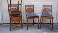 Four wooden dining chairs displayed; two stacked and two standing