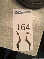 A pair of angular lightning bolt shaped dangle earrings made of 14 karat gold, displayed on a numbered card.